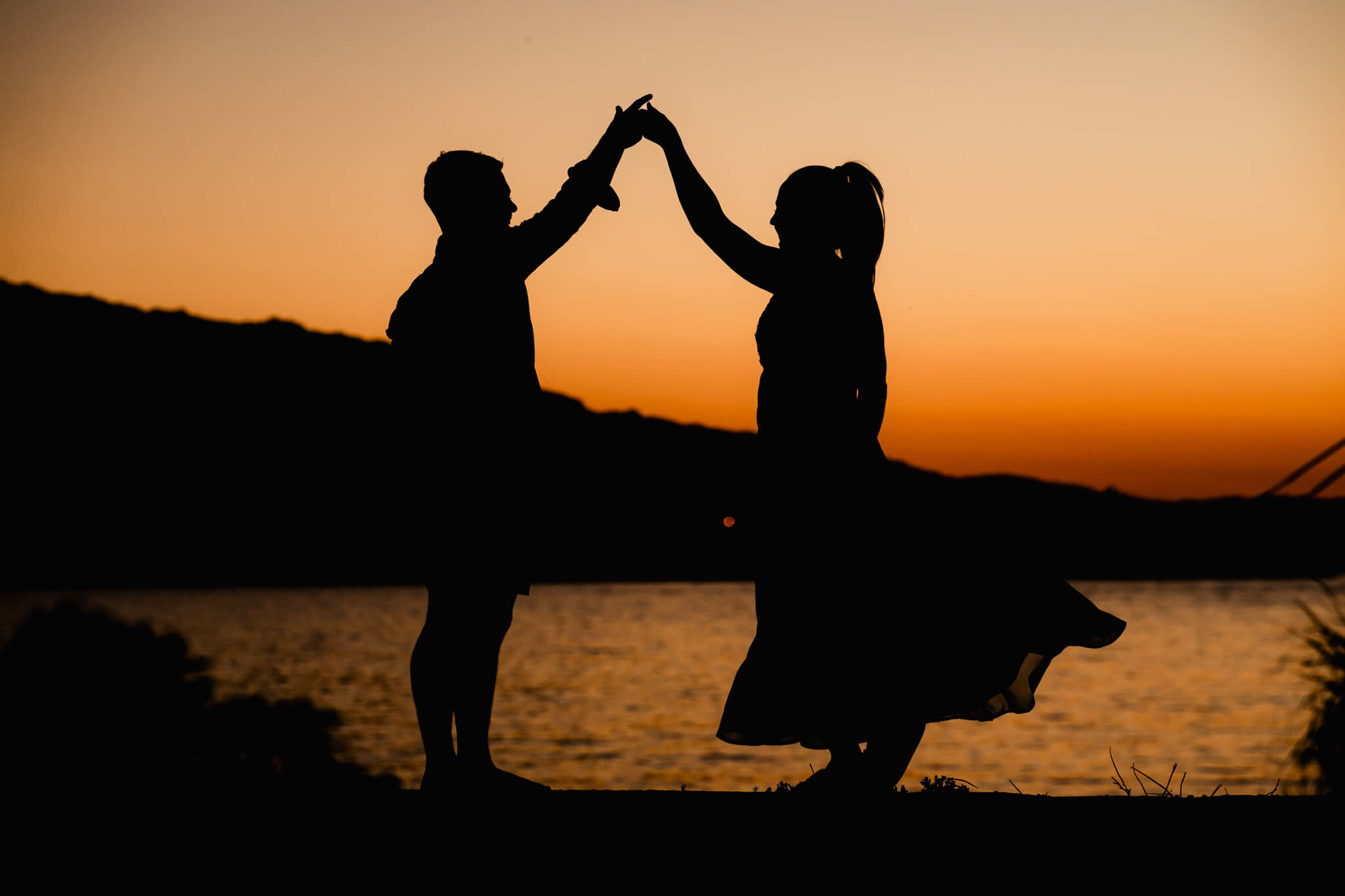 Silhouette of a couple dancing at sunset by the water, symbolizing love and the excitement of planning a dream wedding– How to Plan Your Wedding Day.