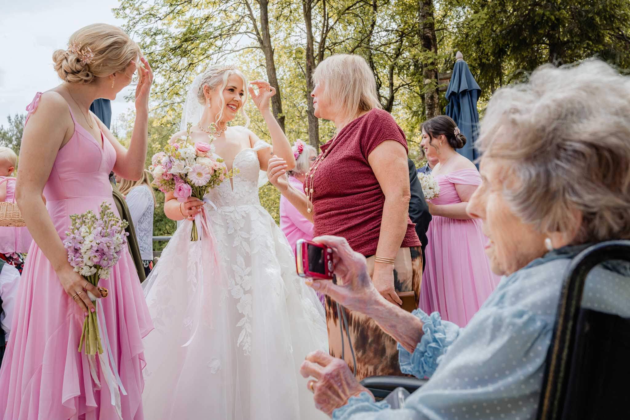 Bride greeting guests as the groom’s grandmother takes a photo in her wheelchair.