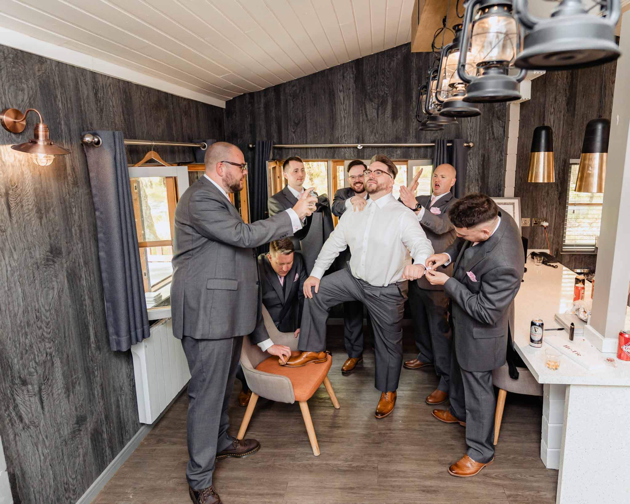 Groom and groomsmen in suits sharing a fun moment while getting ready.