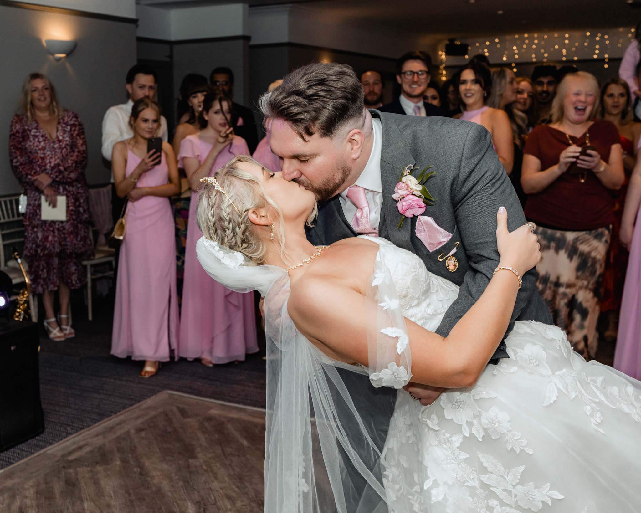 Groom dipping and kissing bride during first dance.