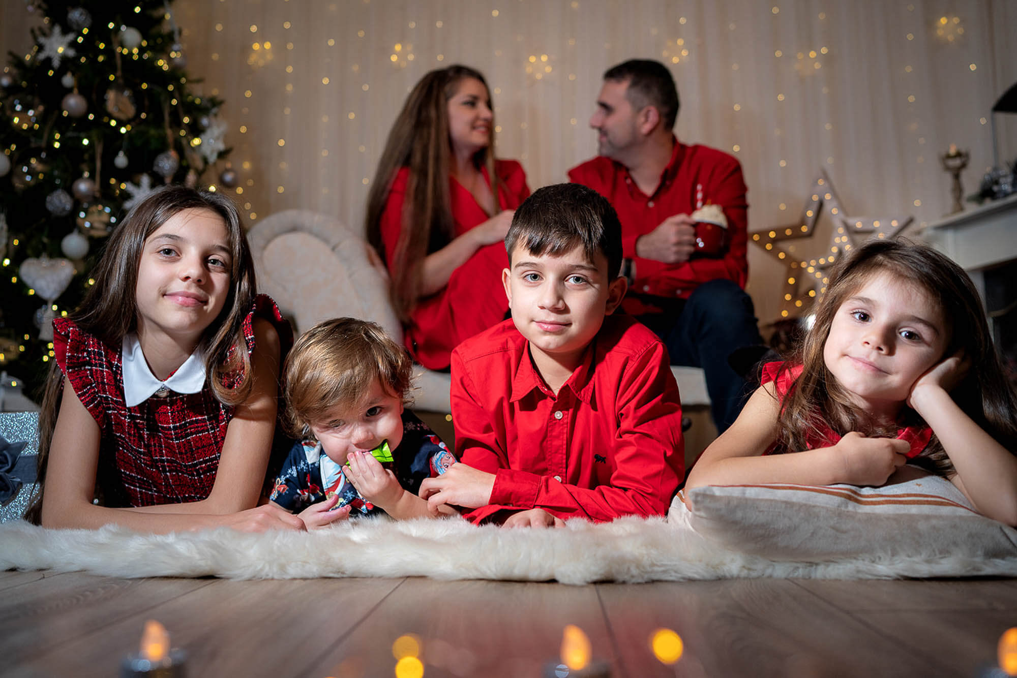 Parents in background while children pose in front during festive family photoshoot at Leeds studio.