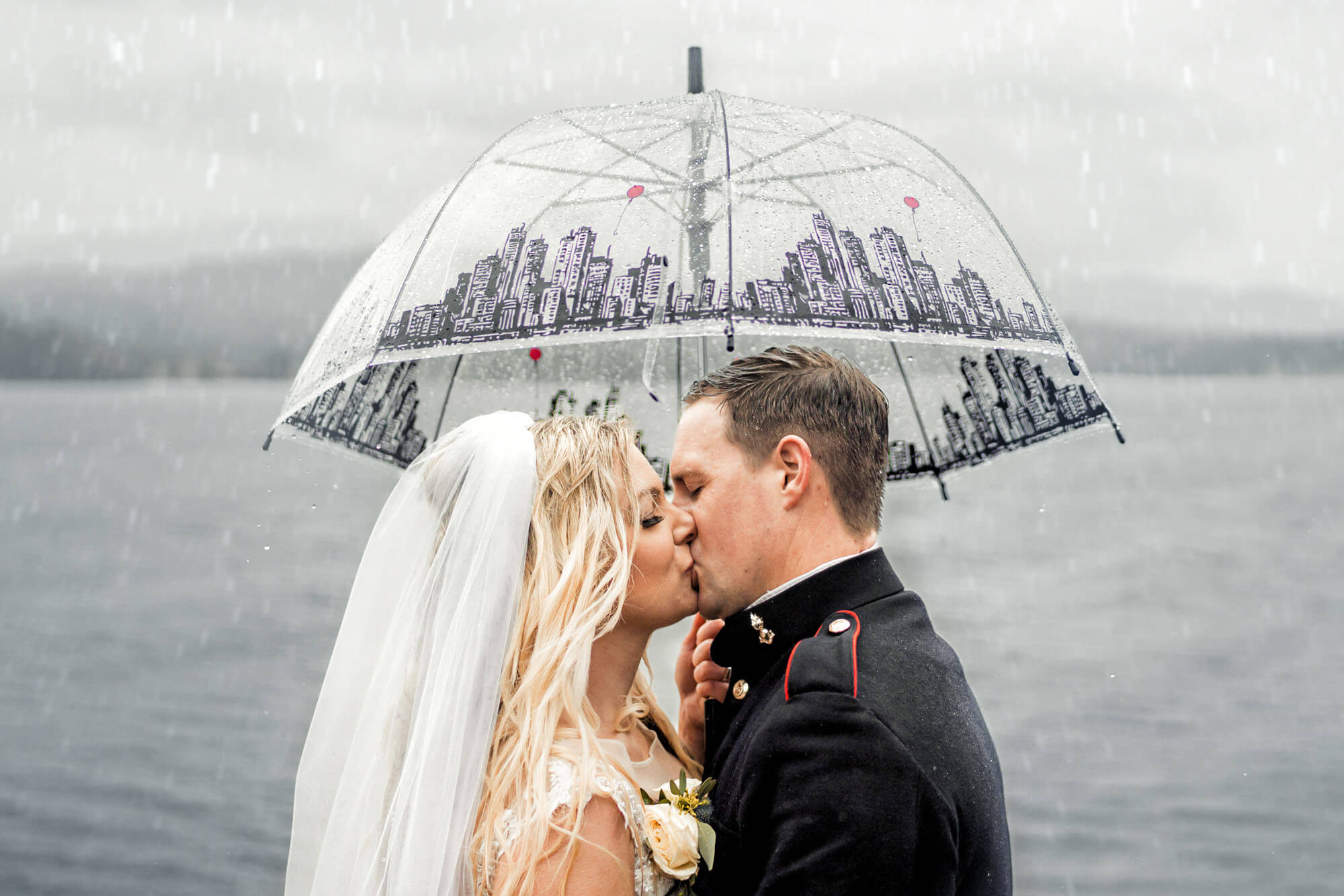 Bride and groom sharing a kiss under a clear umbrella in the rain - captured by Calini Weddings, featured on Love My Dress.