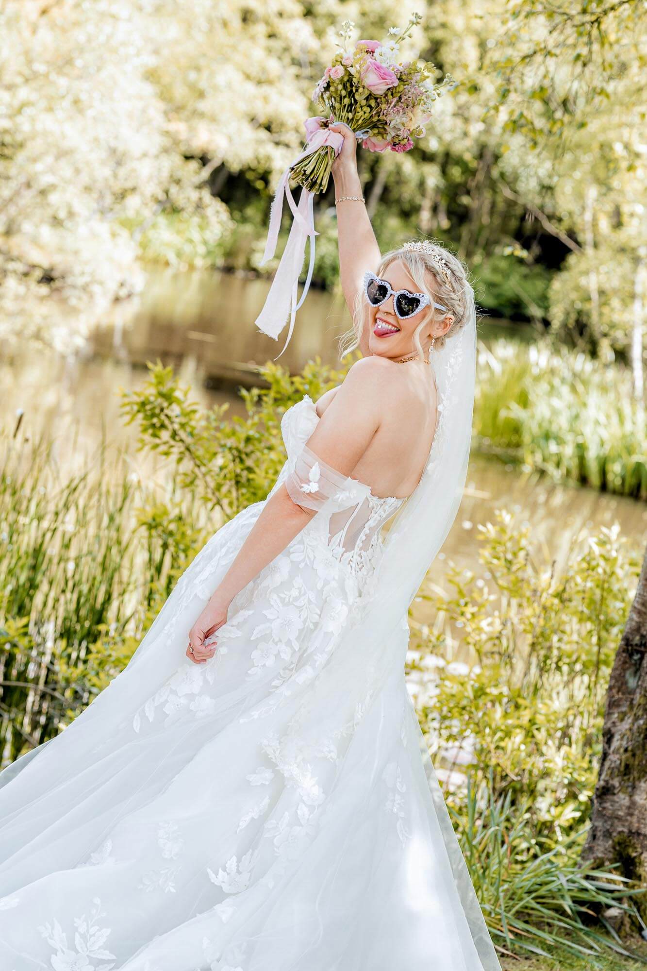 Bride celebrating with sunglasses and bouquet during a fun summer wedding captured by Calini Weddings.