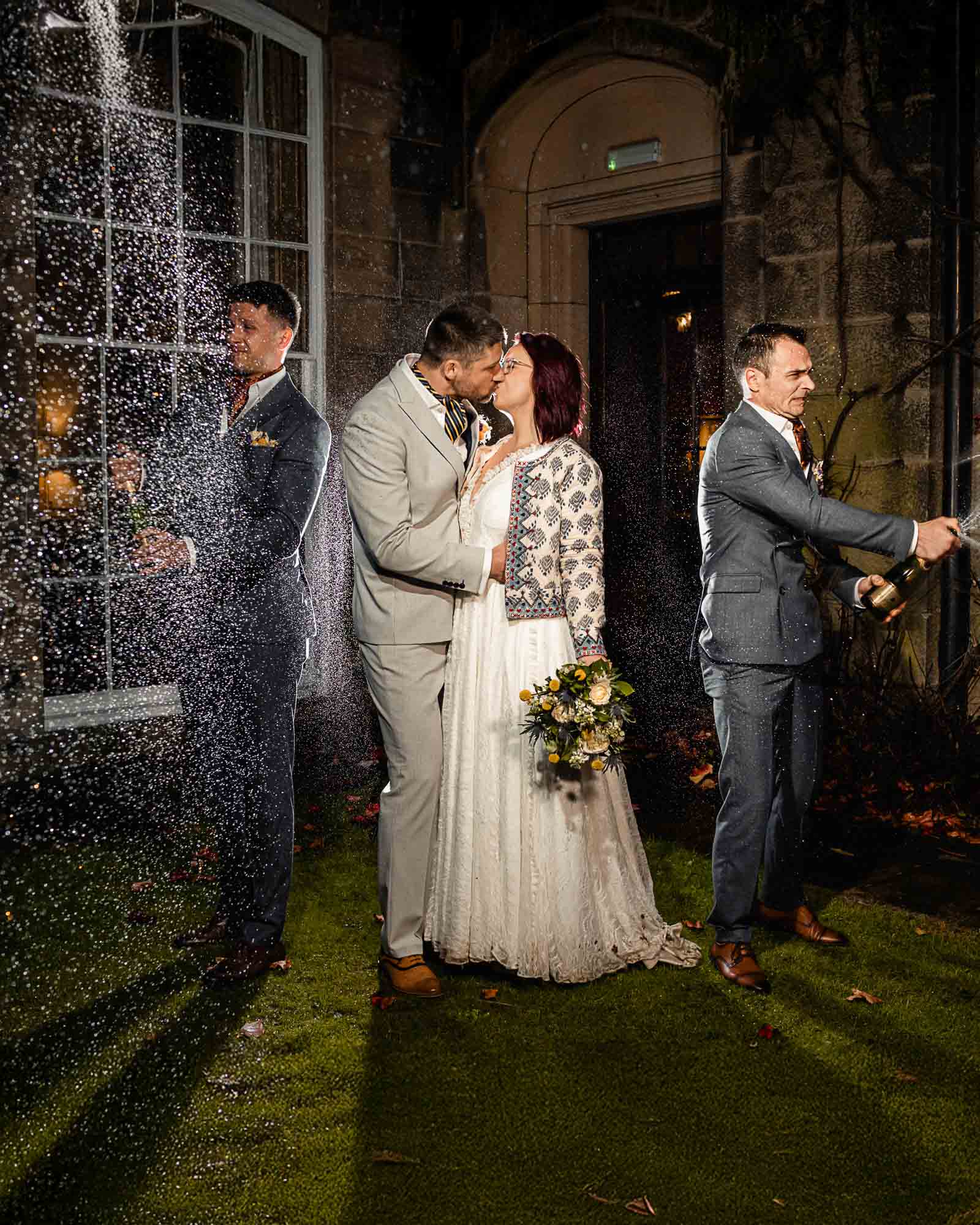 Emotional elopement wedding in Yorkshire as the couple kiss in the rain while champagne is sprayed around them.
