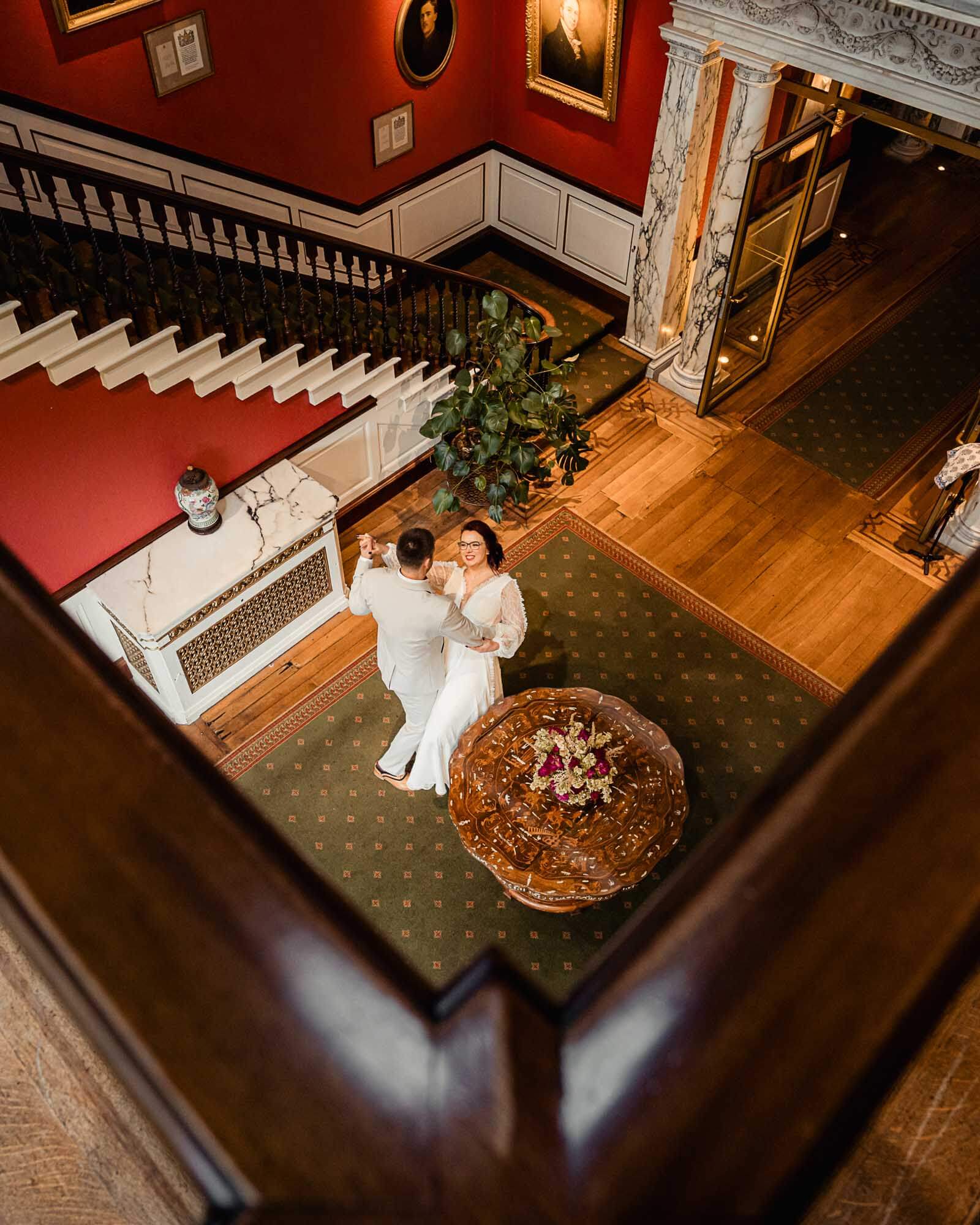 Intimate elopement wedding in Yorkshire as the couple share a quiet dance inside a historic venue, viewed from above.