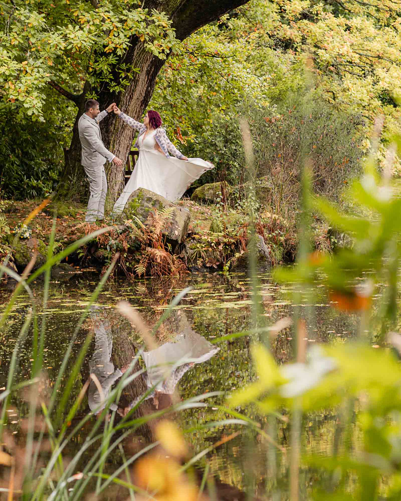 Intimate elopement wedding in Yorkshire as the couple share a quiet moment by a woodland lake surrounded by autumn colours.