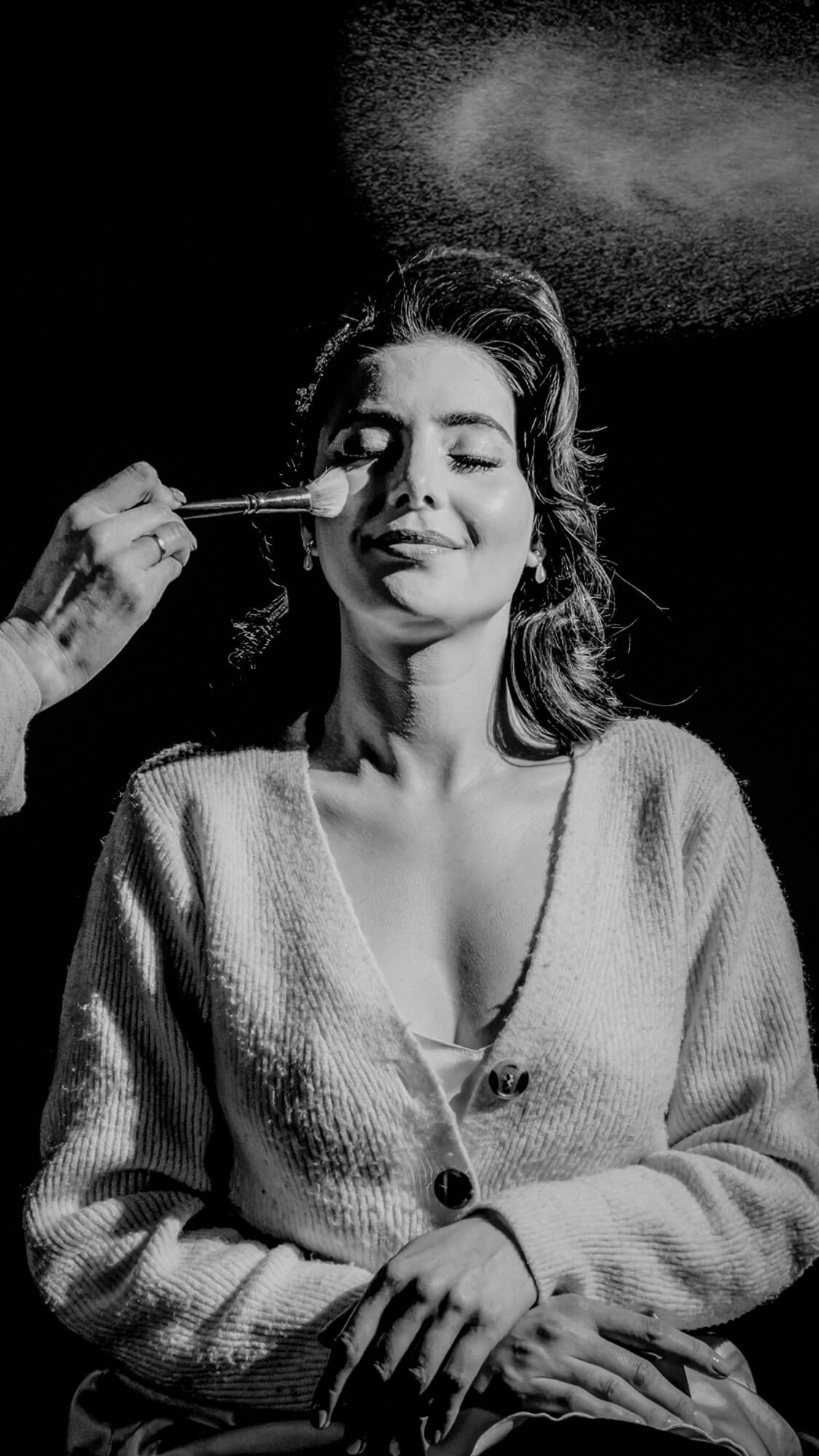 Black and white bridal preparation portrait with makeup brush