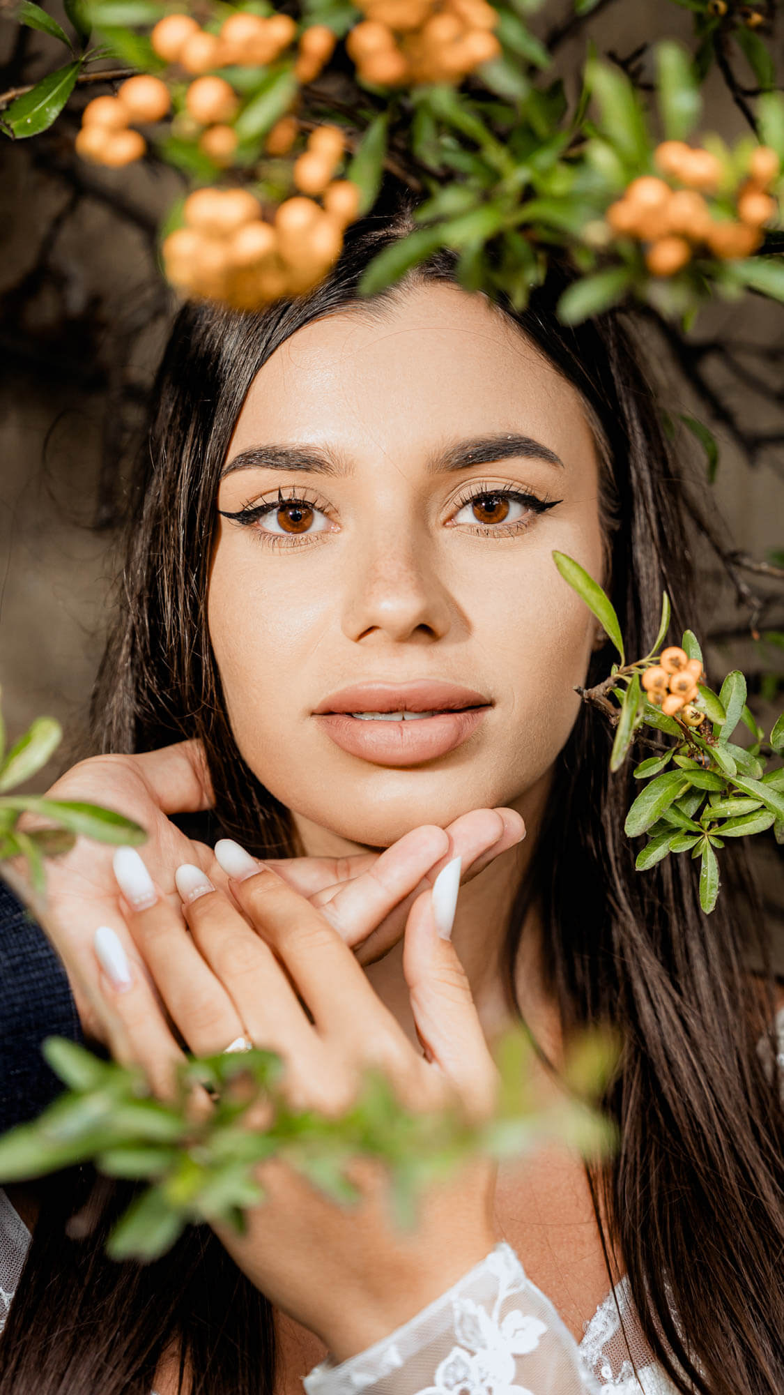 Editorial bridal portrait framed by foliage in soft natural light