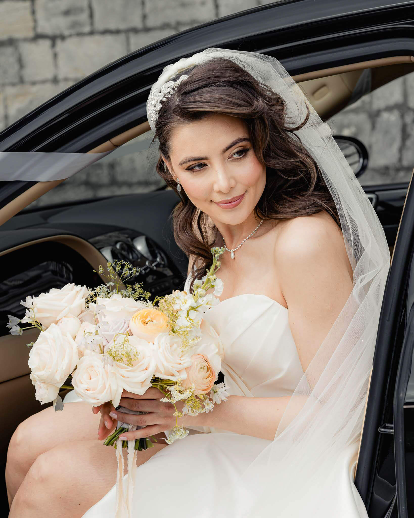 Bride holding bouquet while seated in a car during Hazlewood Castle bridal portraits
