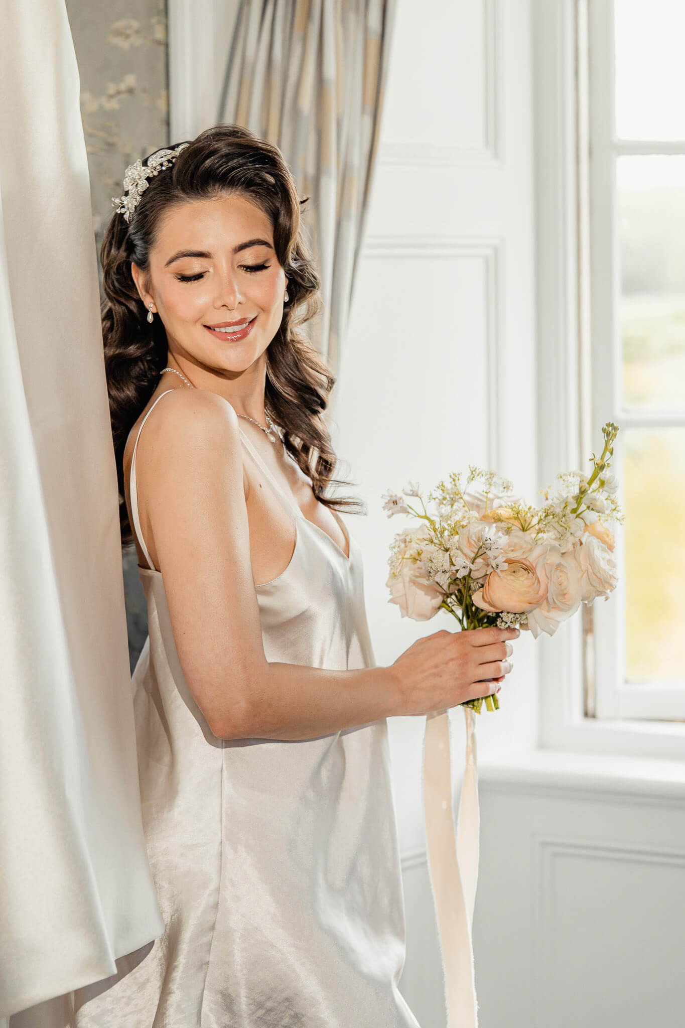 Bride holding her bouquet near a window during editorial bridal portraits at Hazlewood Castle