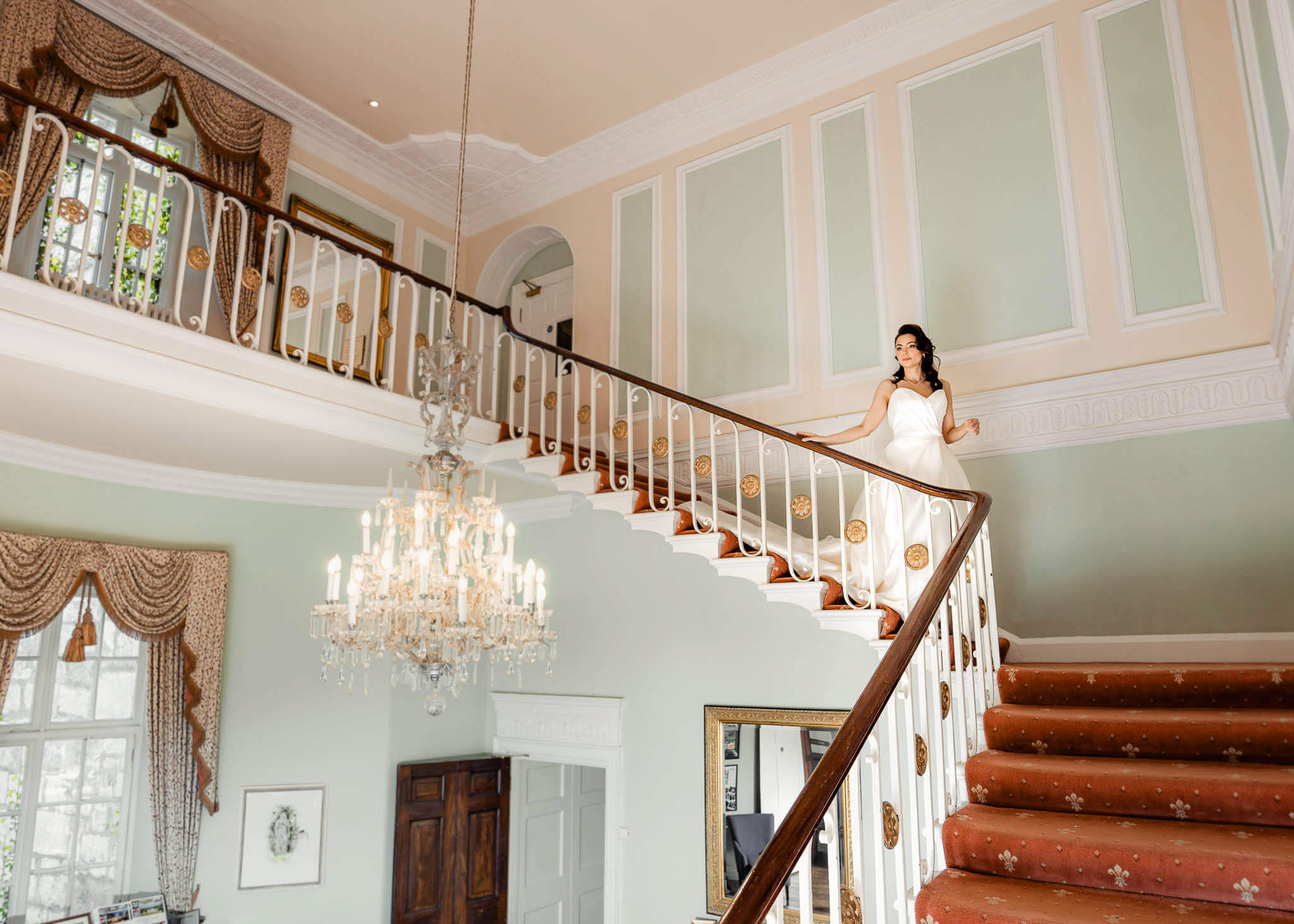 Wide view of bride standing on the grand staircase inside Hazlewood Castle