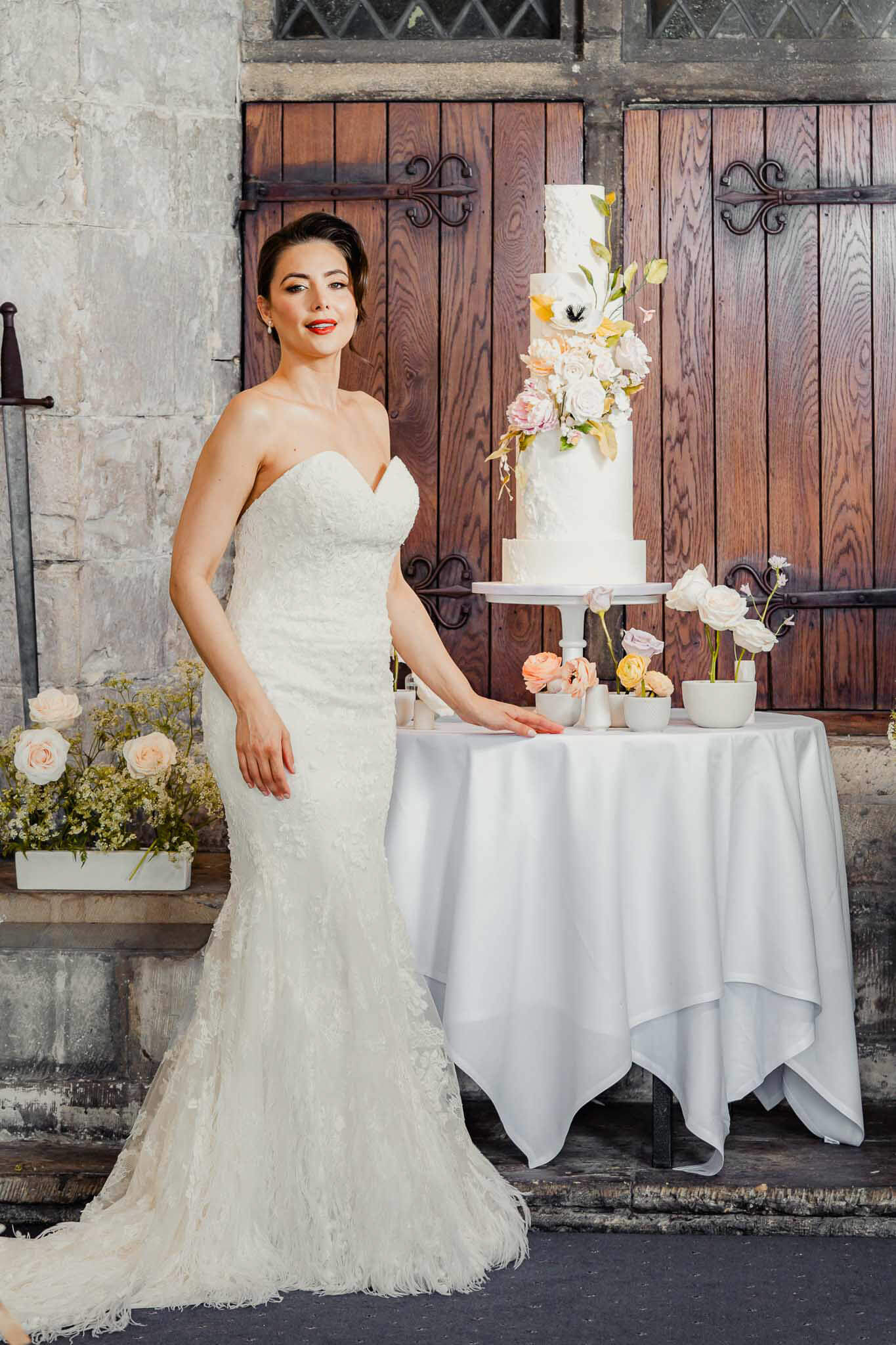 Bride standing beside an elegant wedding cake during portraits at Hazlewood Castle