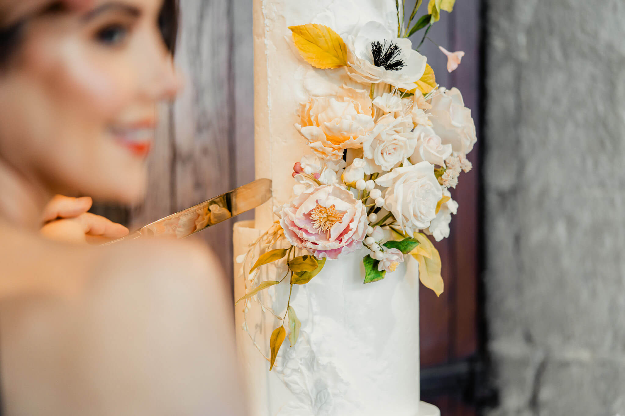 Close-up moment of the bride cutting a wedding cake decorated with flowers