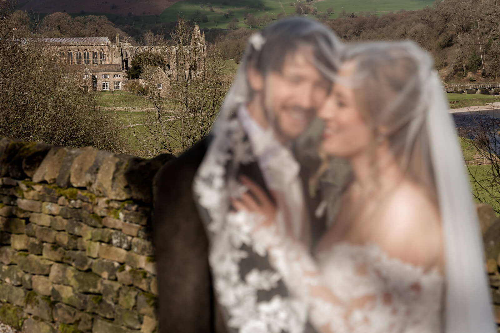 Soft focus bride and groom portrait with Bolton Abbey in the background in Yorkshire
