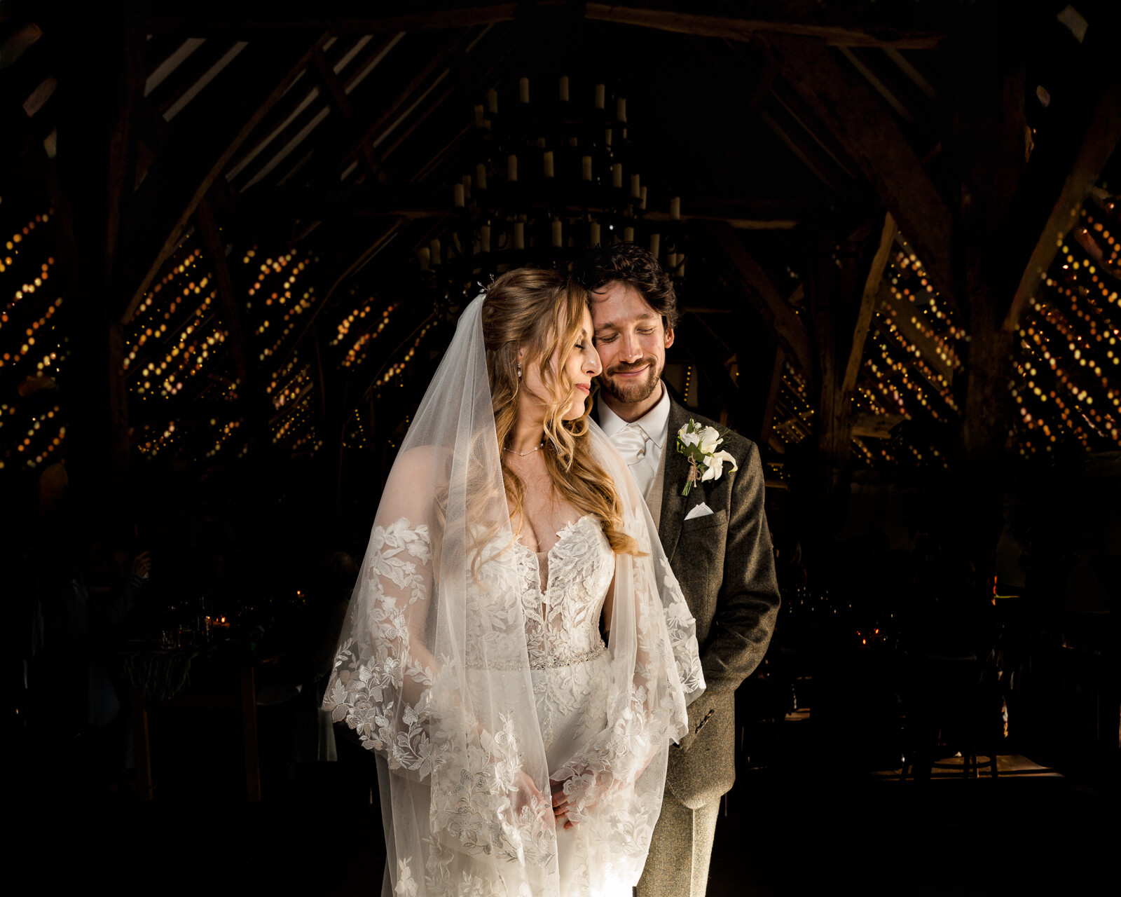 Romantic evening portrait of a bride and groom inside a candlelit rustic barn with warm ambient lighting
