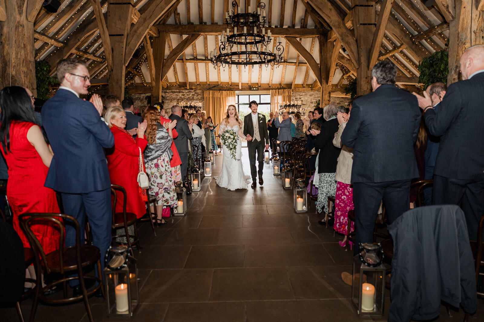 Bride and groom walking back down the aisle at The Tithe Barn at Bolton Abbey as guests applaud