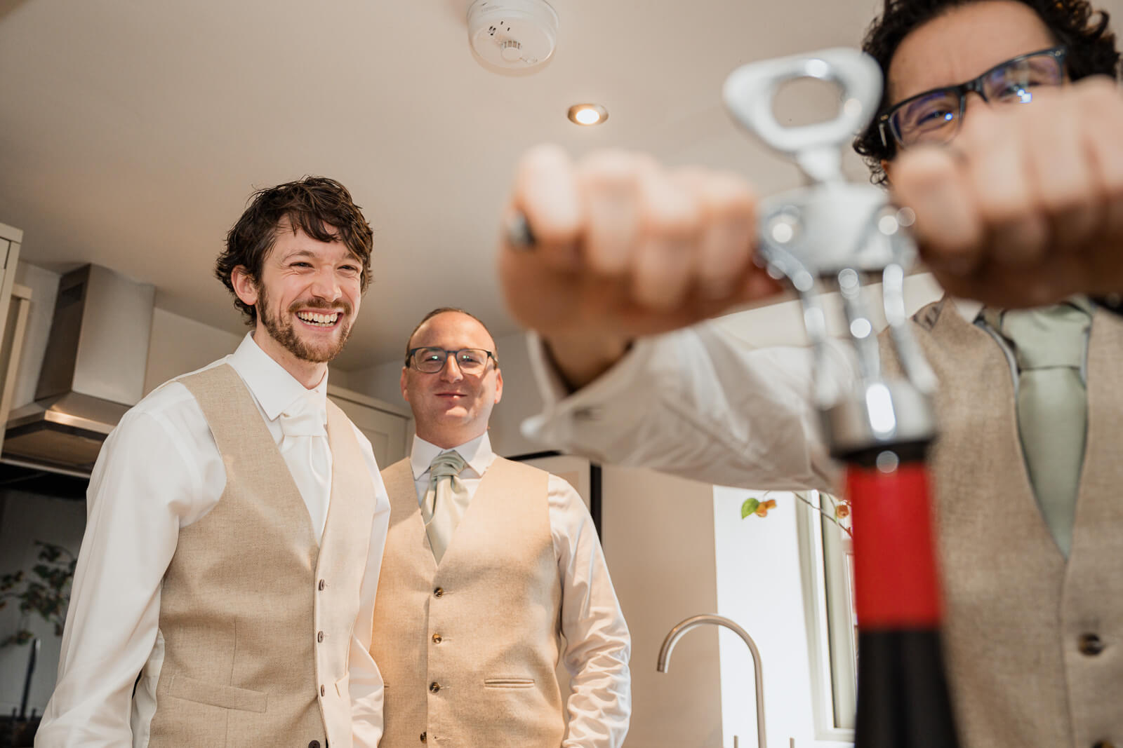 Groom and groomsmen opening a bottle during morning preparations with relaxed candid moment