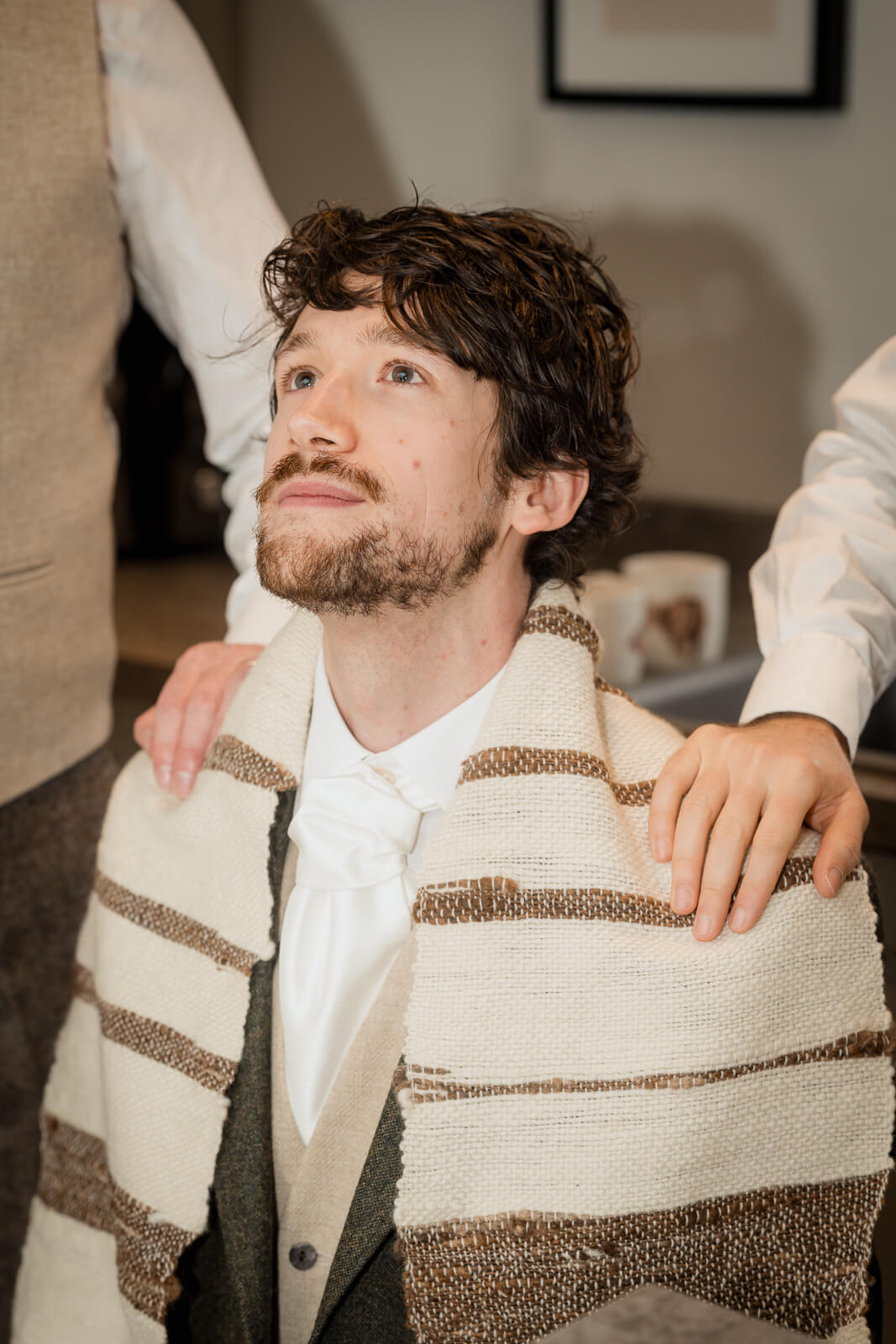 Groom having tie adjusted during morning wedding preparations at The Tithe Barn at Bolton Abbey