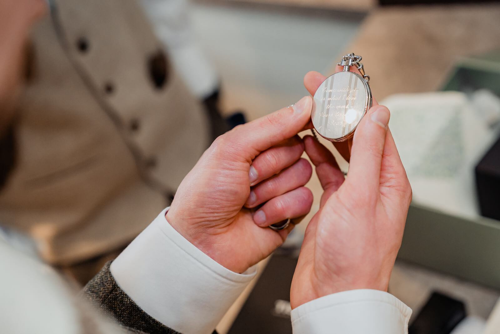 Groom holding engraved pocket watch gift during wedding morning preparations