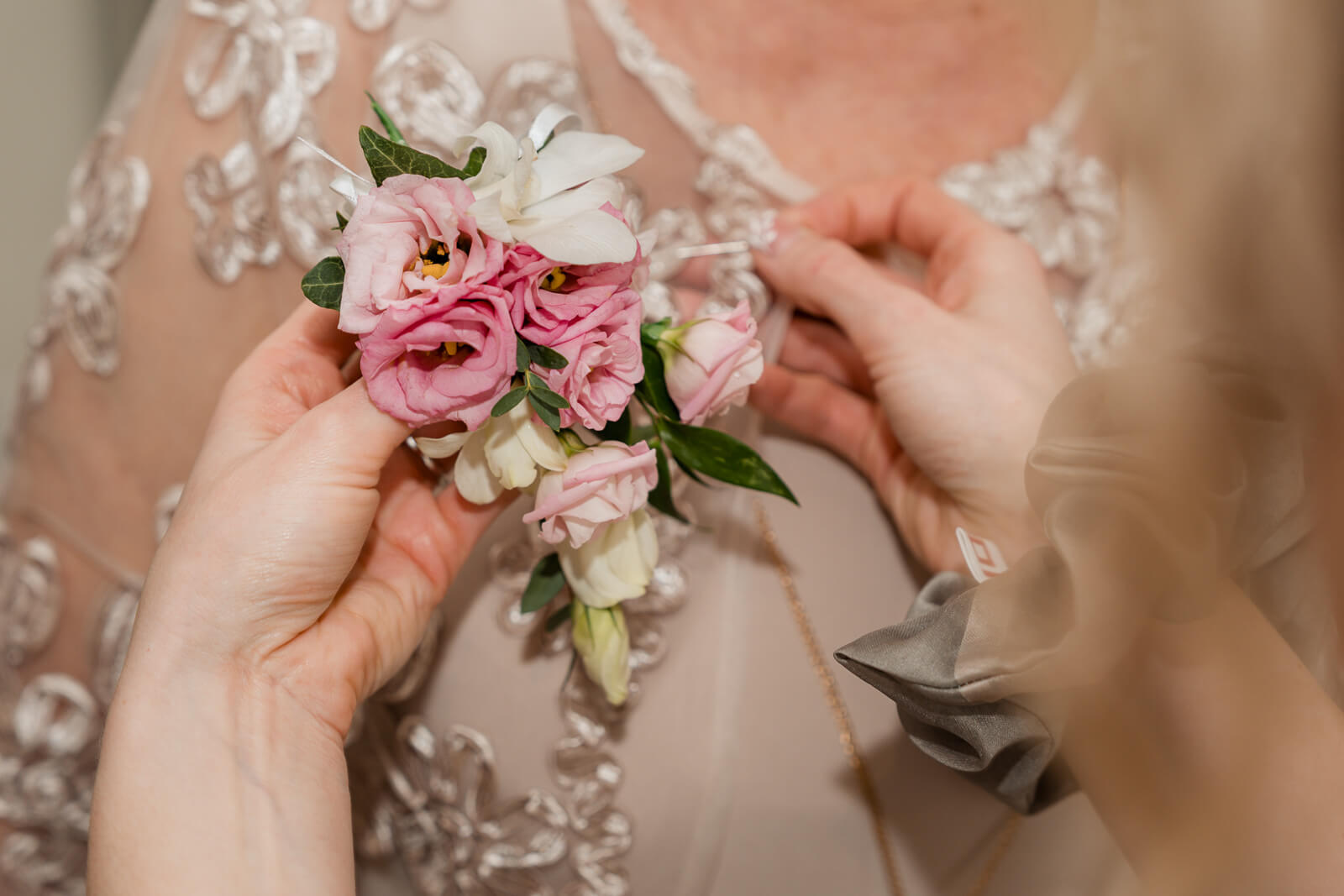 Bridal boutonniere being pinned onto dress during wedding morning preparations