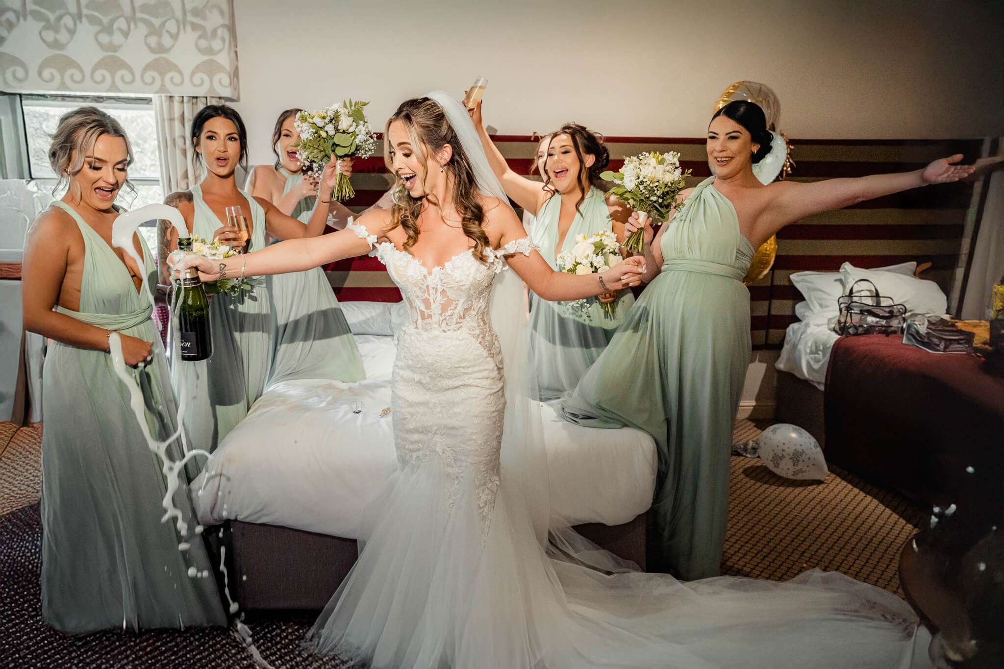 Bride popping champagne with bridesmaids celebrating