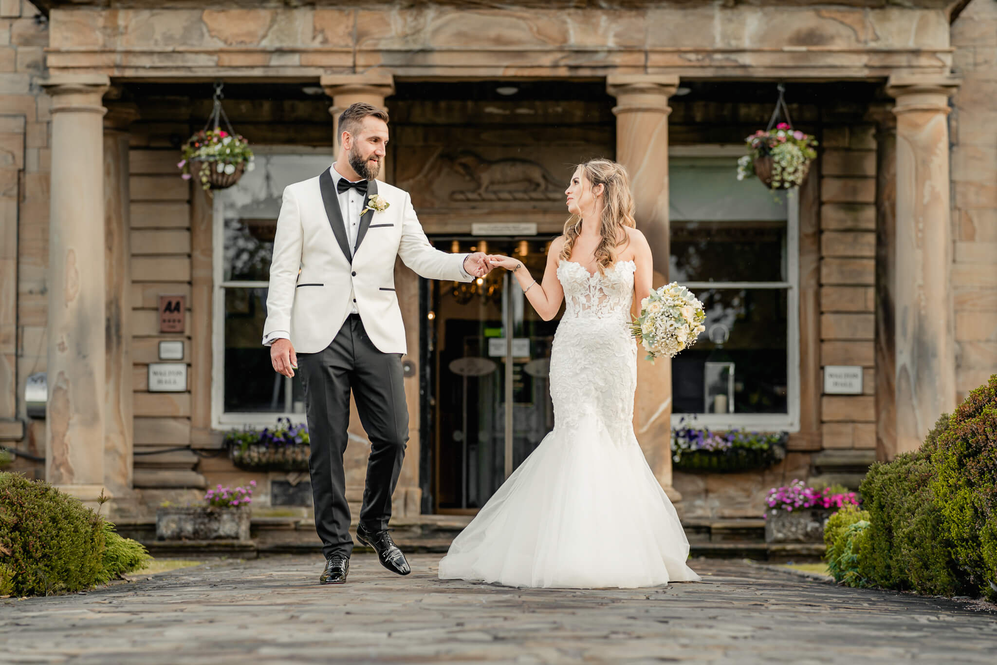 Bride and groom walking hand in hand in front of Waterton Park Hotel