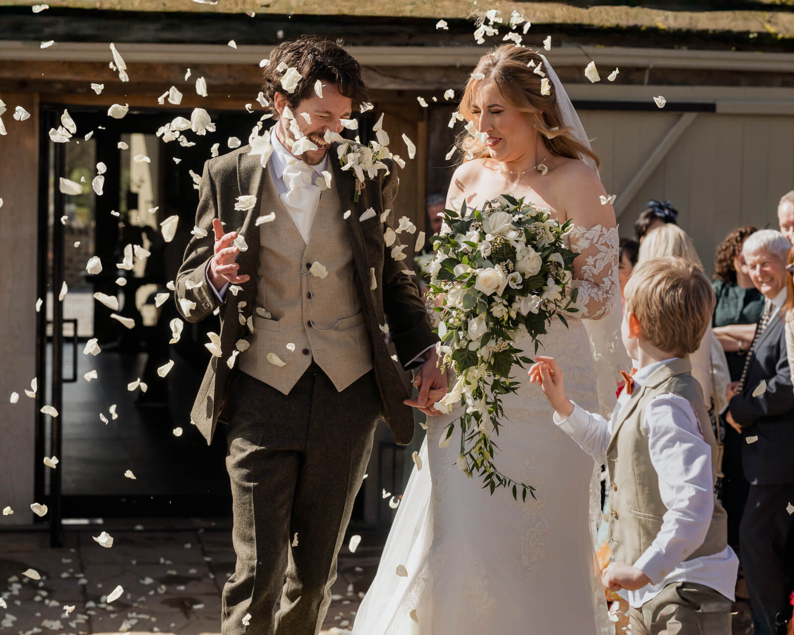 Bride and groom walking through confetti after wedding ceremony surrounded by guests