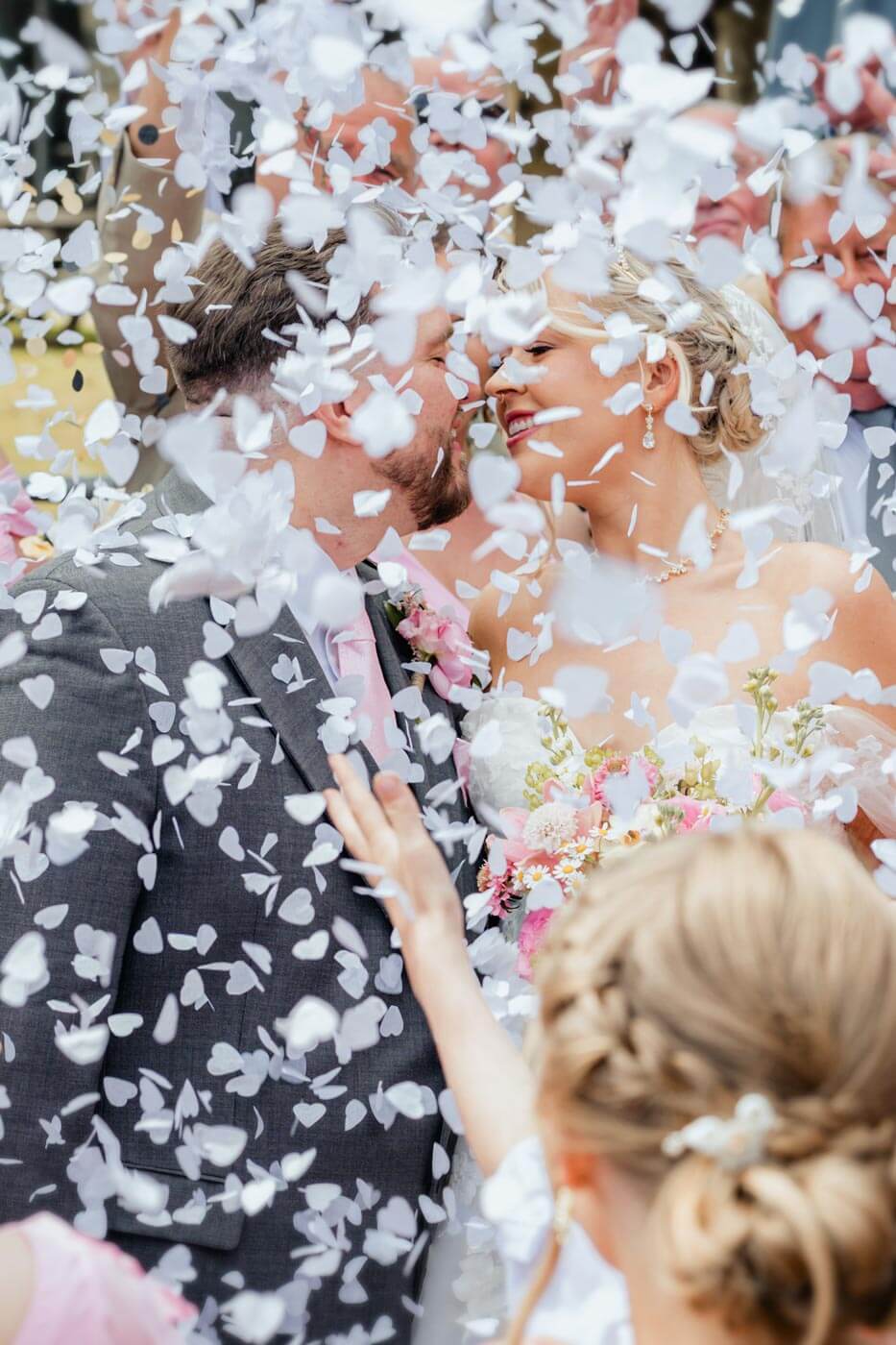 Yorkshire wedding photographer capturing romantic confetti moment with bride and groom smiling during outdoor ceremony