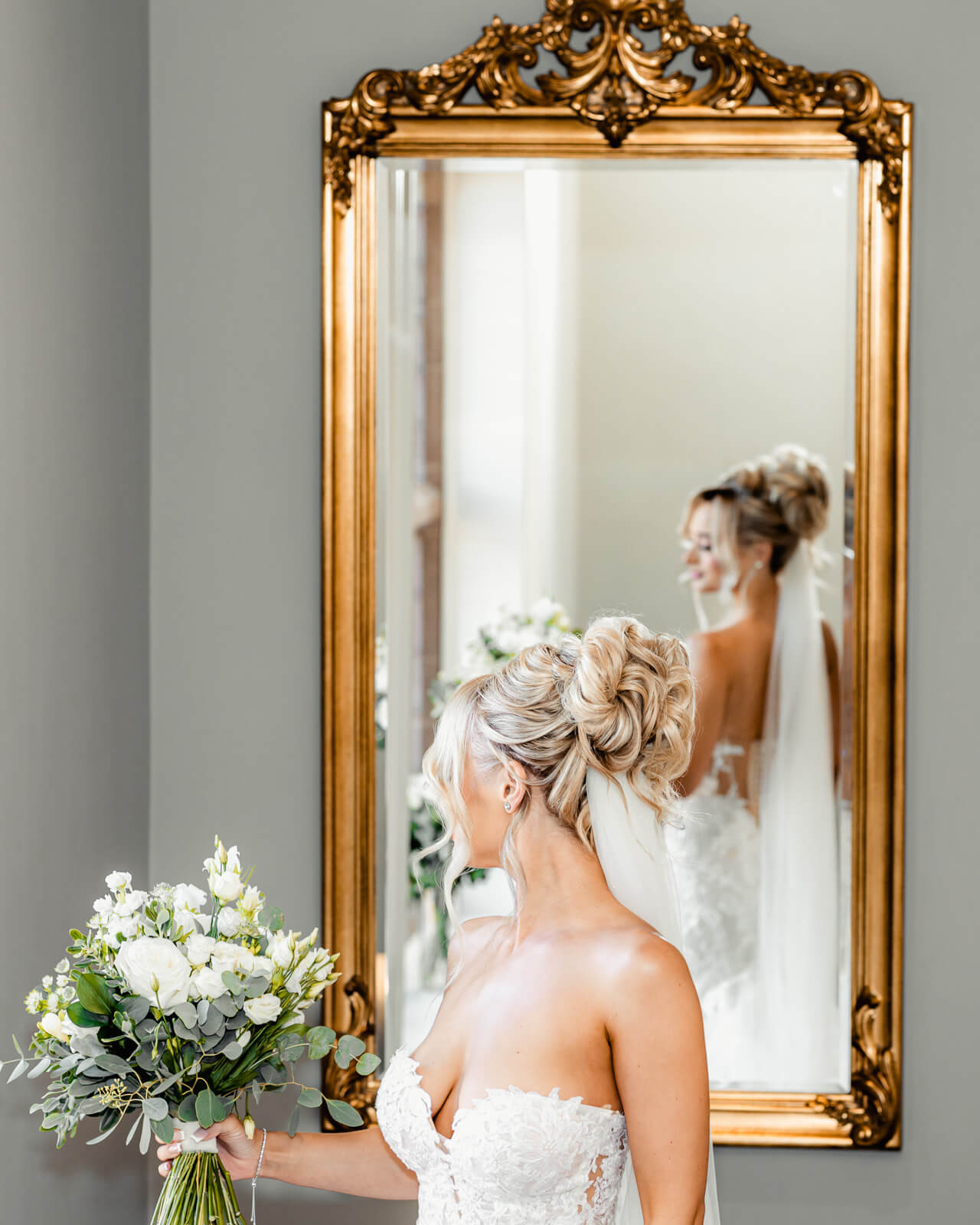 Bride holding bouquet reflected in ornate mirror at Colshaw Hall Country Estate