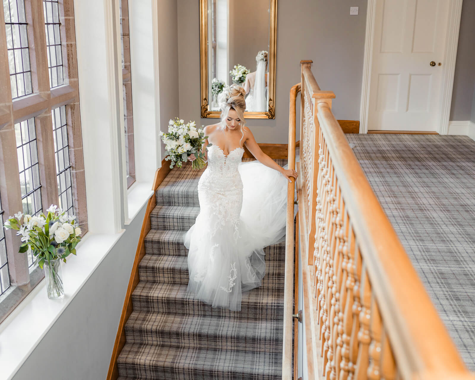 Bride walking down staircase holding bouquet at Colshaw Hall Country Estate