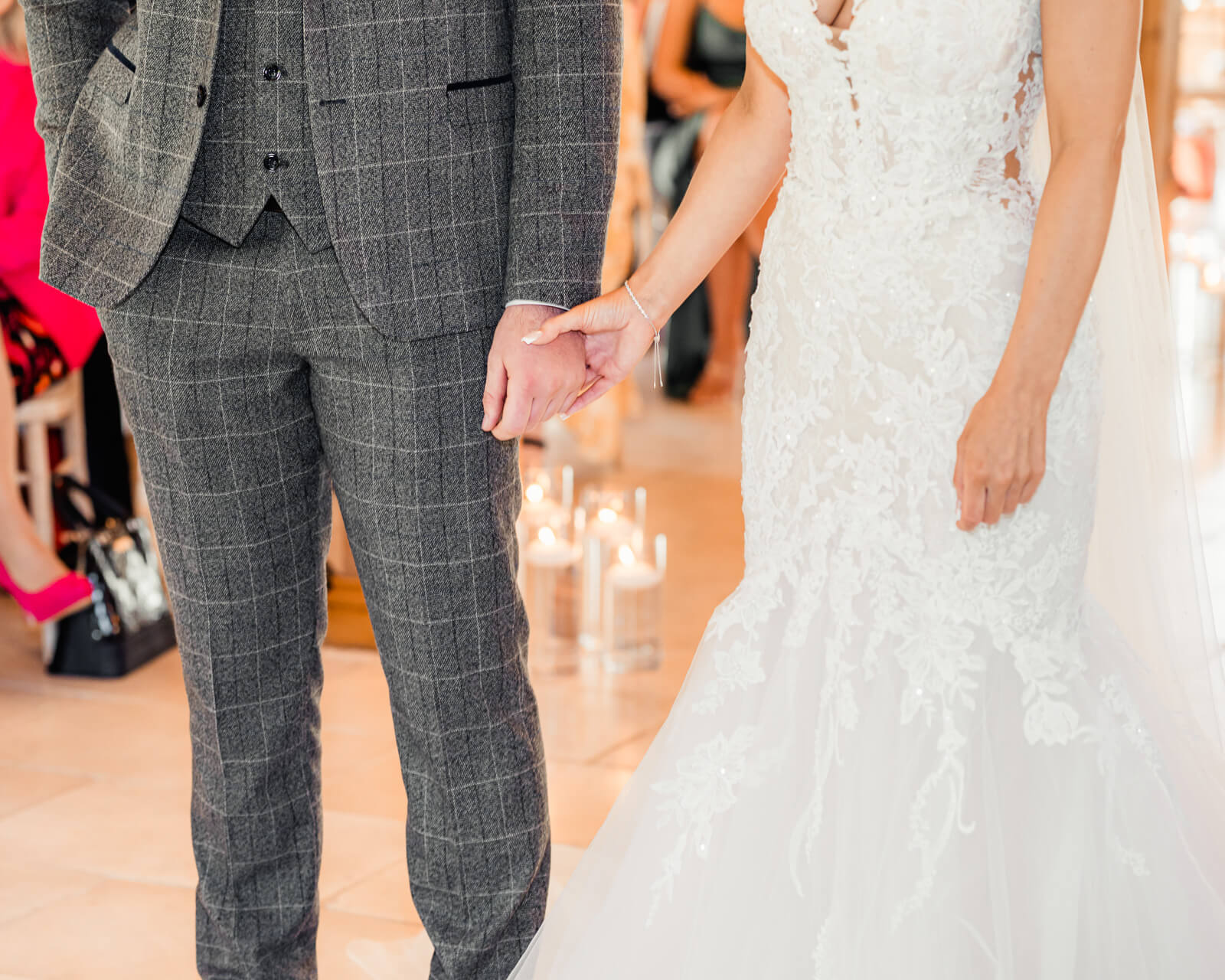 Bride and groom holding hands during ceremony with soft candlelight and elegant details