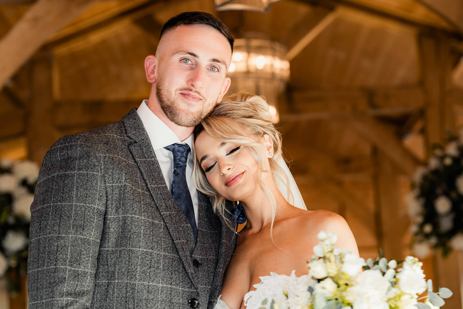 Bride resting her head on groom’s shoulder during intimate wedding portrait with soft lighting