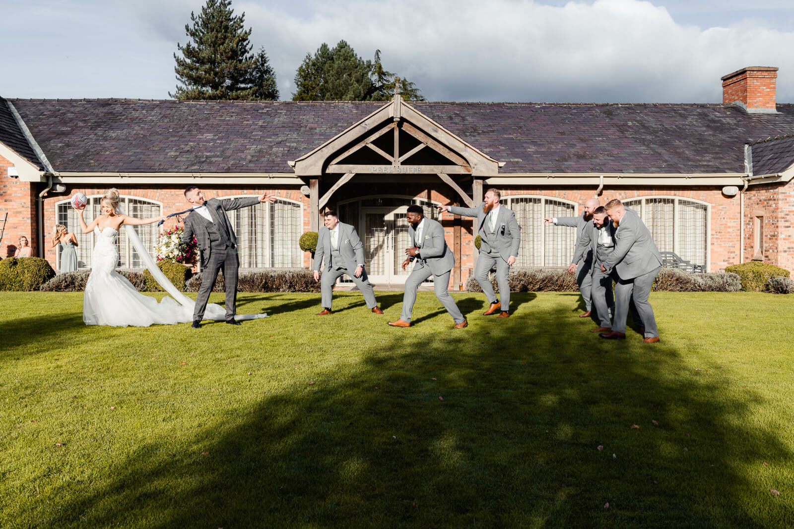 Bride pulling groom while groomsmen playfully react during Elegant Wedding at Colshaw Hall Country Estate
