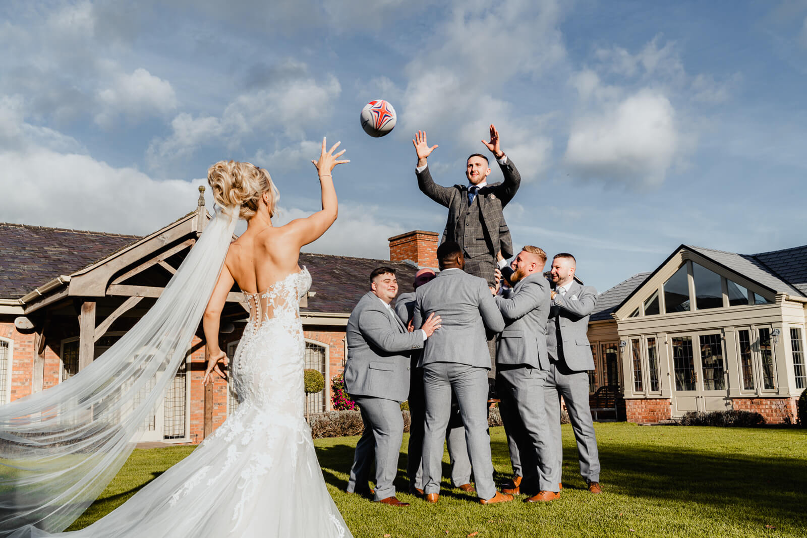 Groom lifted by groomsmen reaching for a ball during Elegant Wedding at Colshaw Hall Country Estate