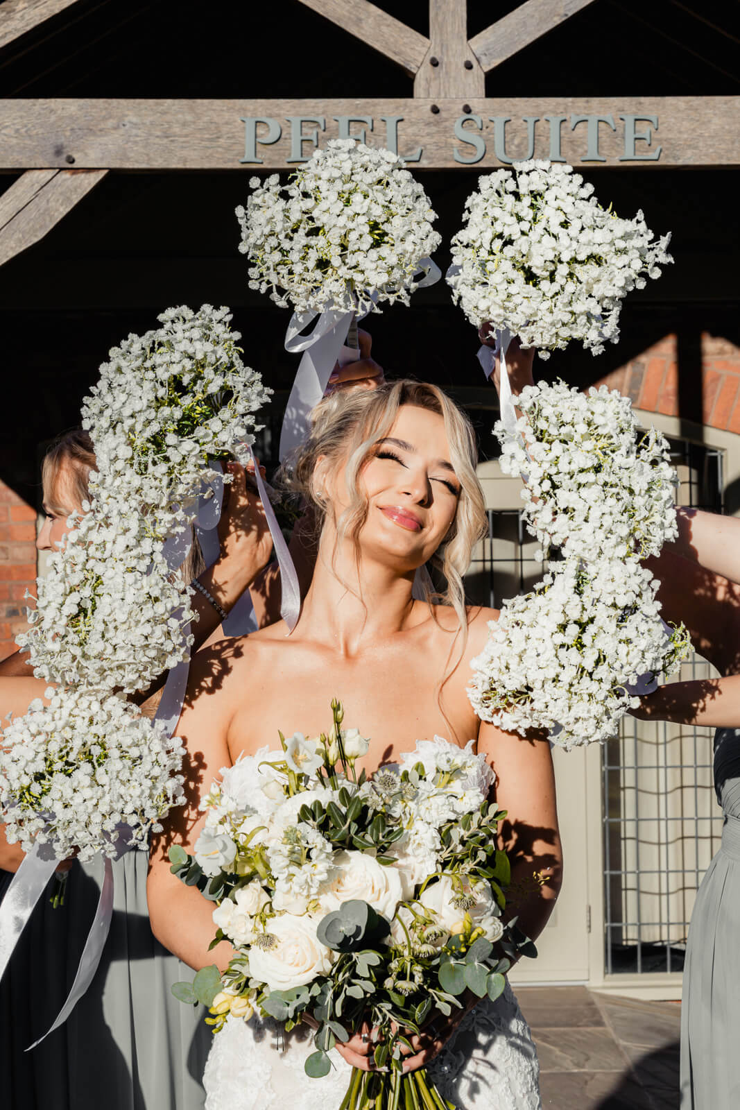 Bride holding bouquet surrounded by bridesmaids’ flowers during Elegant Wedding at Colshaw Hall Country Estate