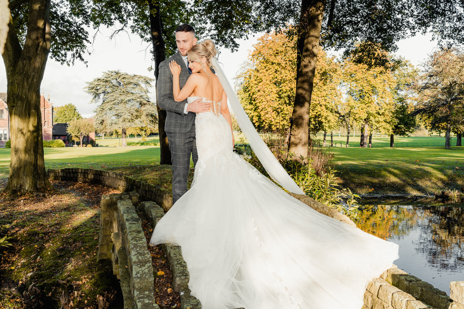 Bride and groom on stone bridge during Elegant Wedding at Colshaw Hall Country Estate with flowing veil and scenic grounds
