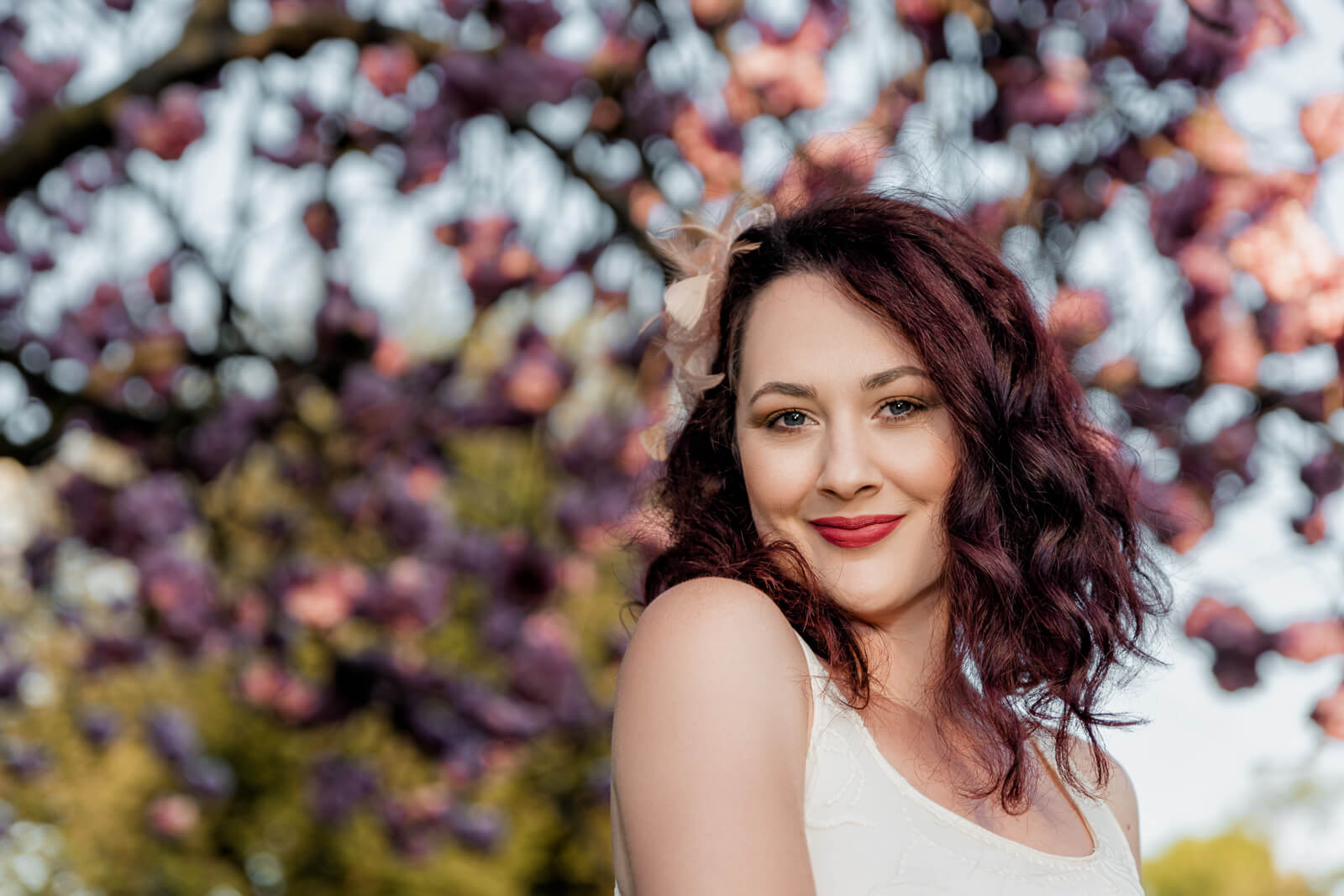 Woman smiling under cherry blossoms in Harrogate during a spring photo session