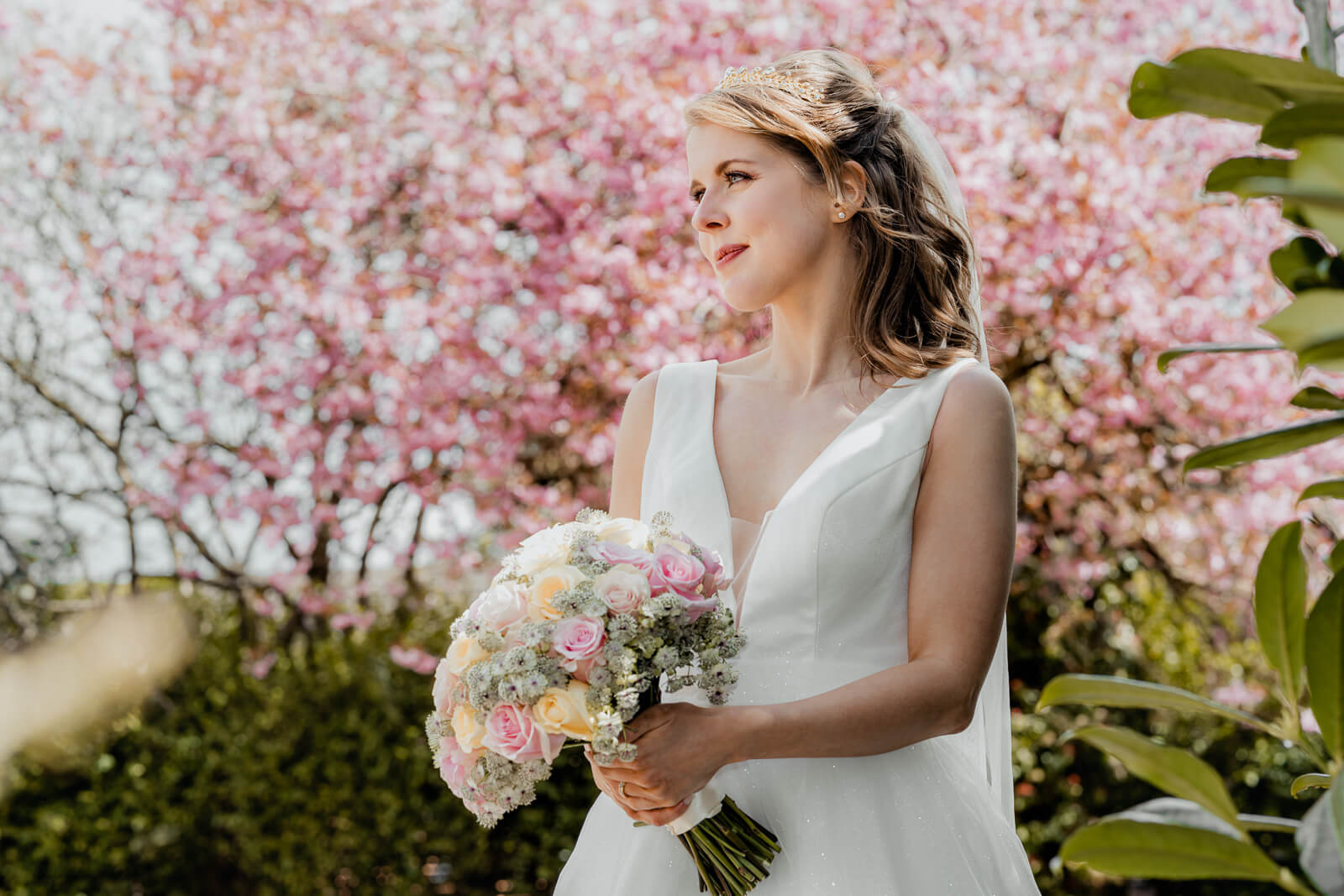 Bride holding a bouquet under cherry blossom trees in Harrogate during a spring photo session