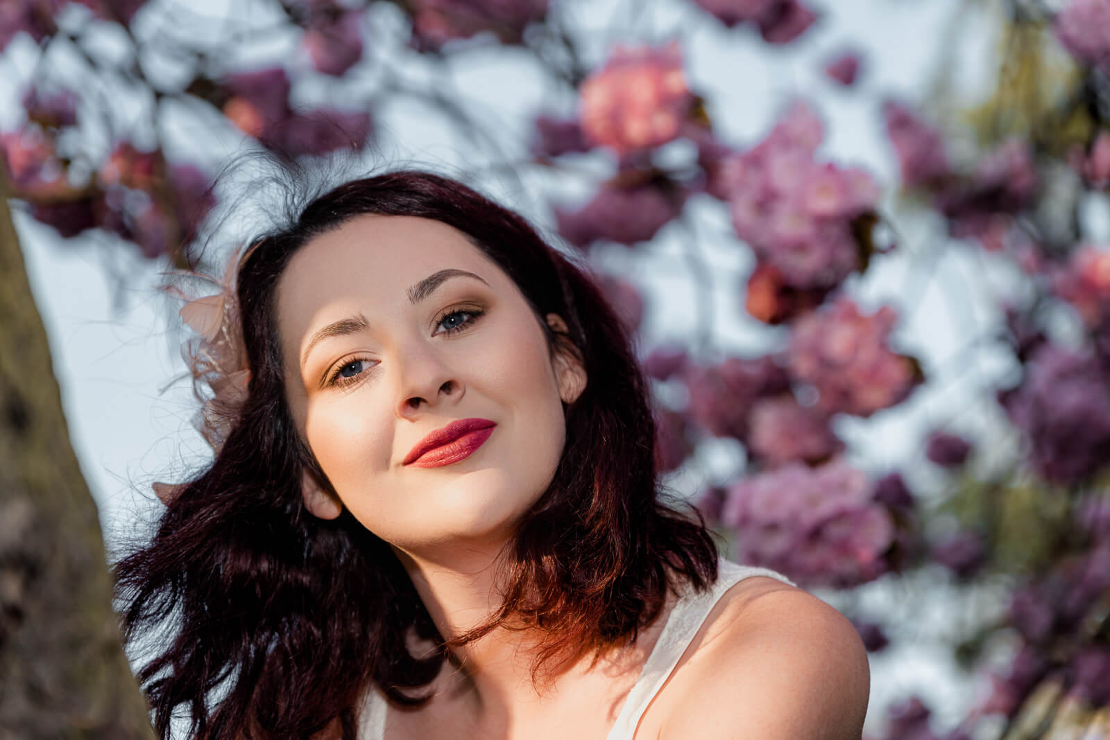 Close-up portrait of a woman under cherry blossoms in Harrogate during golden hour