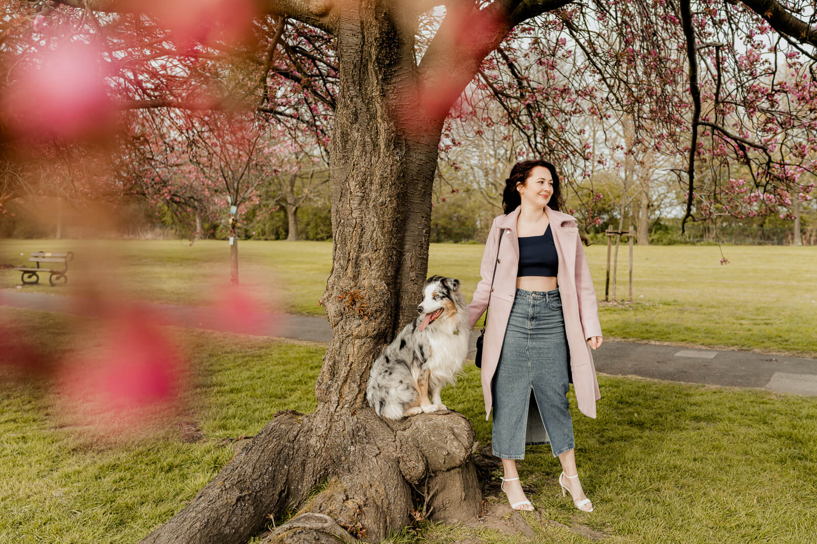 woman and her dog standing beside a tree with blossoms in the foreground
