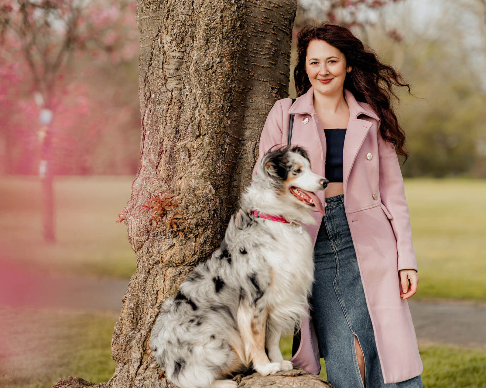 woman and her dog sitting by a tree with pink blossoms