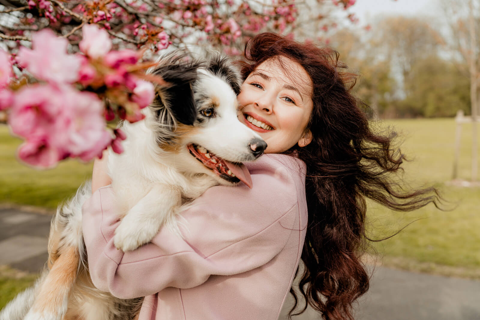Smiling woman hugging her dog under cherry blossoms in Harrogate during spring