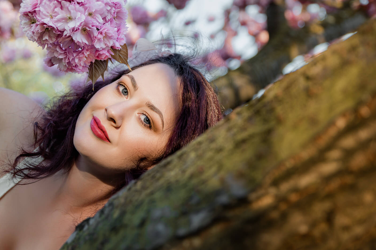 Creative portrait of a woman lying by a tree under cherry blossoms in Harrogate