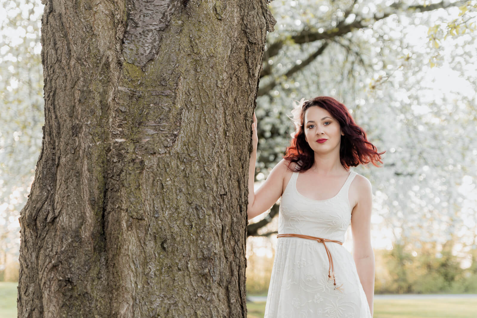 Woman standing beside a tree with spring blossoms in Harrogate looking at camera
