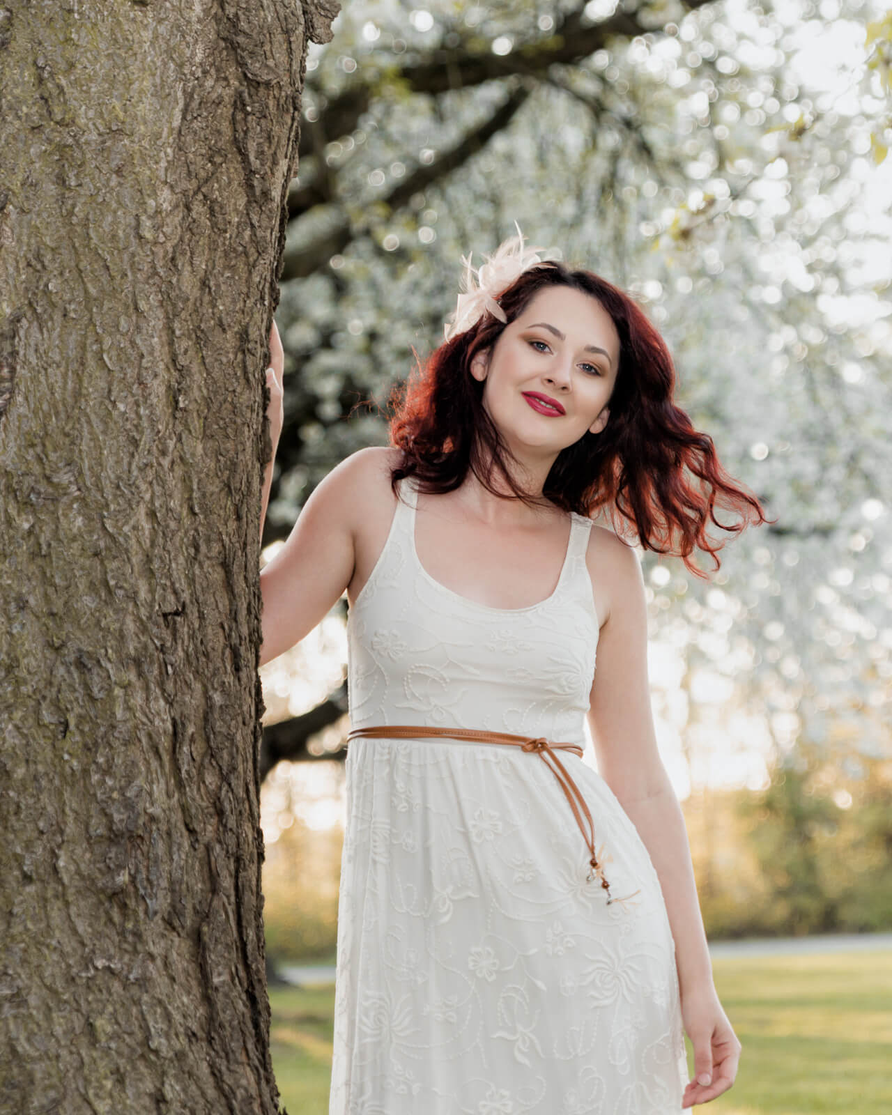 Woman leaning by a tree with cherry blossoms in Harrogate during a spring session
