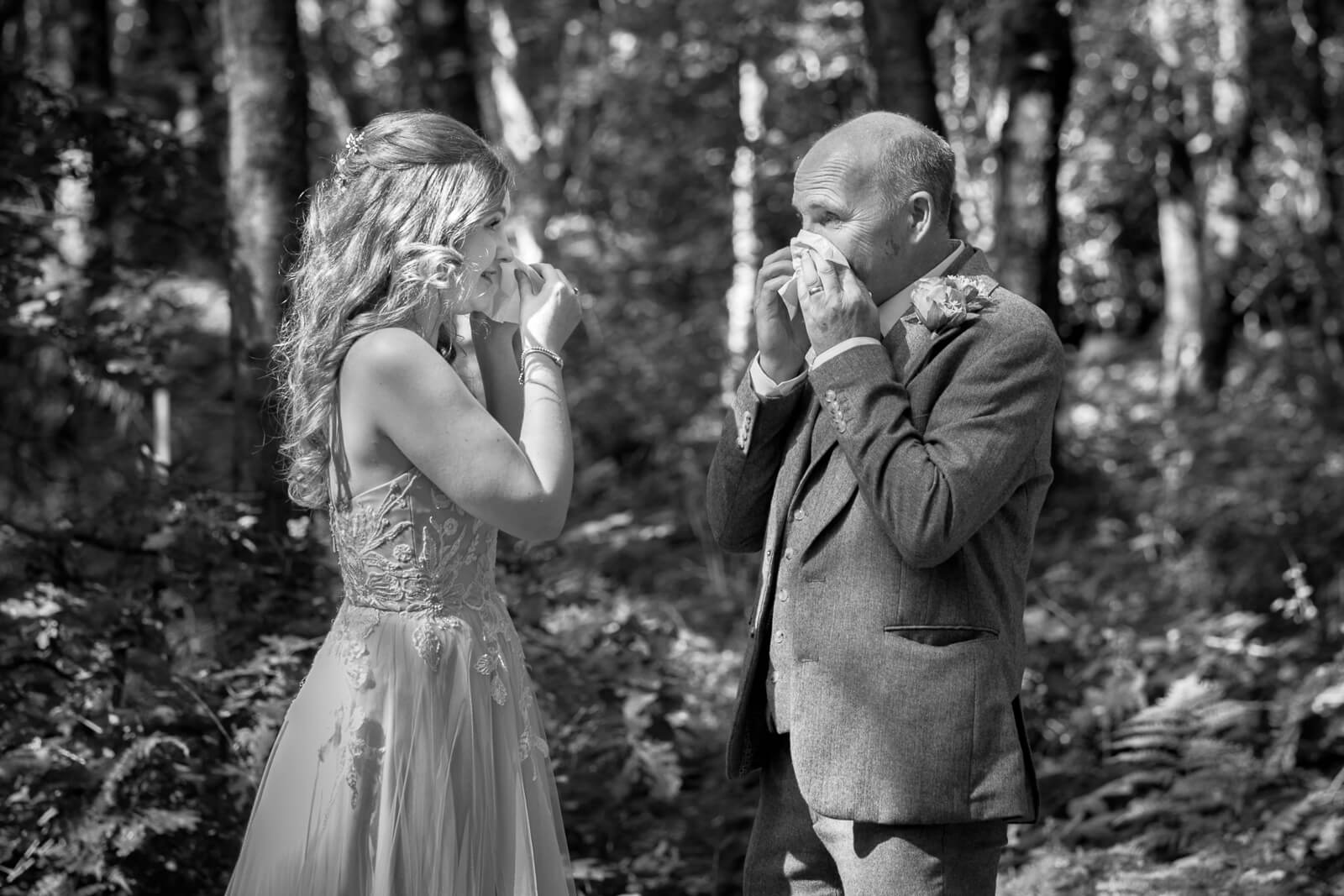 Bride and father sharing an emotional first look in woodland setting
