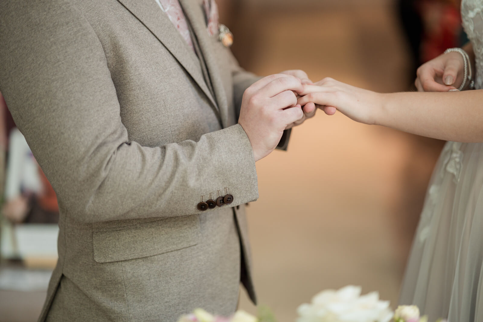 Close up of groom placing wedding ring on bride’s finger during ceremony at Chevin Country Park