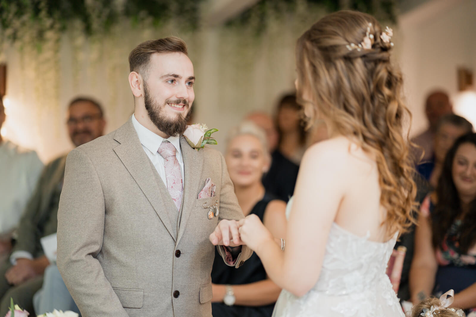 Bride placing wedding ring on groom’s finger during ceremony at Chevin Country Park
