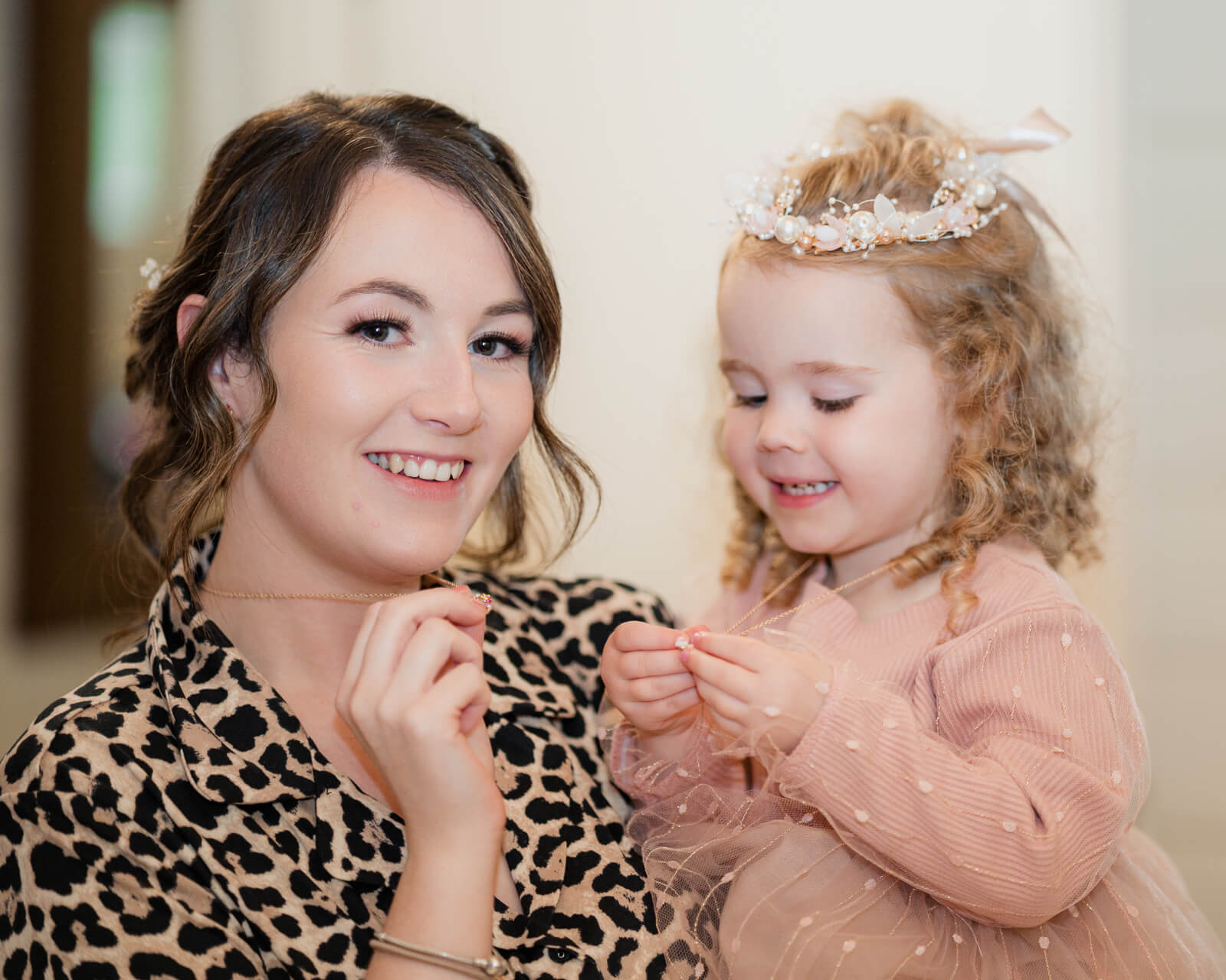 Bride and flower girl smiling while getting ready together in the morning