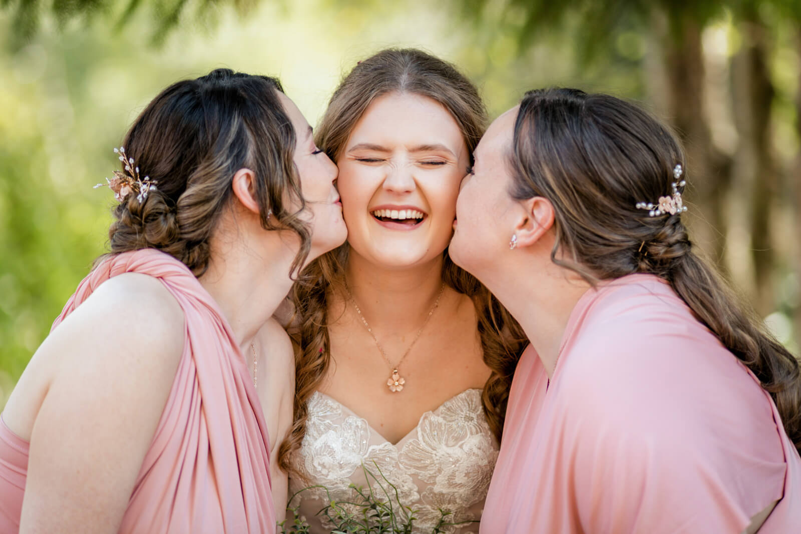 Bride laughing with bridesmaids kissing her cheeks at Chevin Country Park wedding